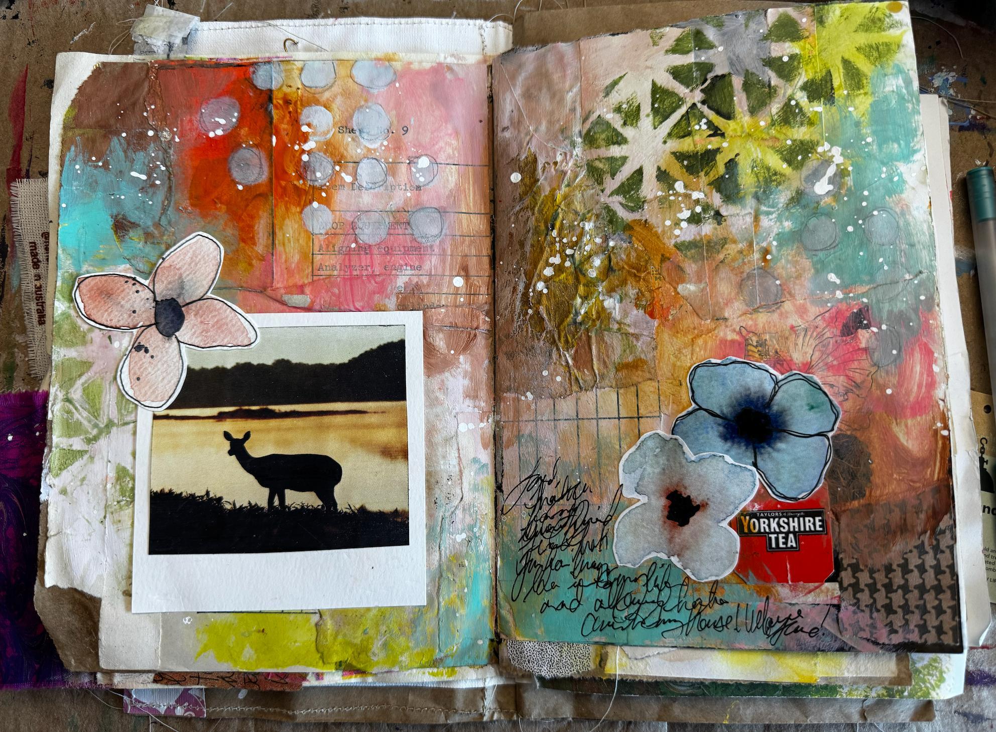 Open art journal spread with colourful mixed media pages, painted flowers, a polaroid photo of a deer silhouette at sunset, a Yorkshire Tea label, and handwritten notes