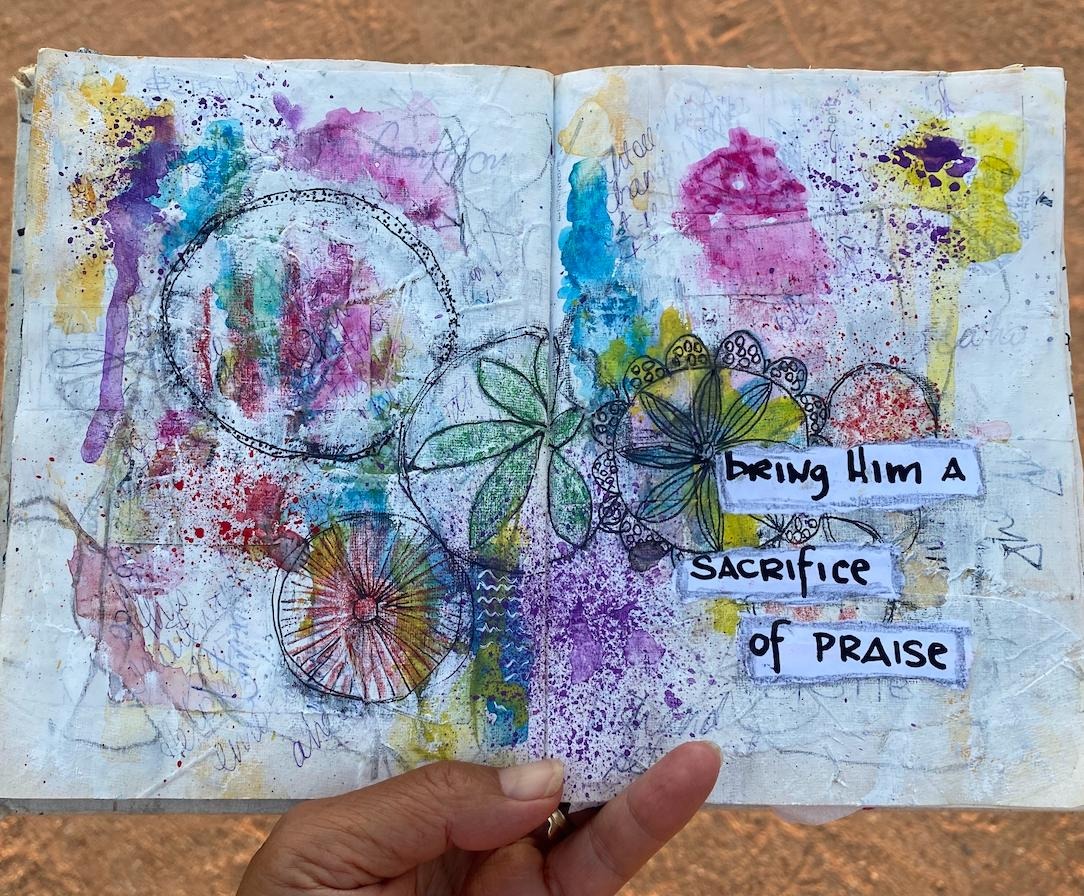 Hands holding open a colourful painted art journal spread
